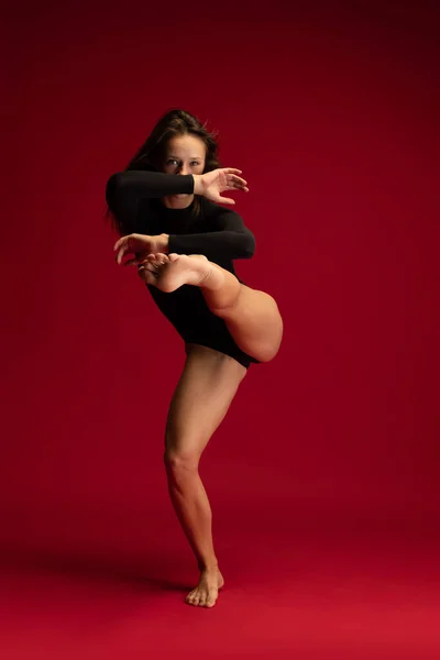 Widok z przodu aparat młoda dziewczyna emocji, piękna kontemplacja kobieta tancerka porusza się dynamicznie izolowane na ciemnoczerwonym tle. — Zdjęcie stockowe