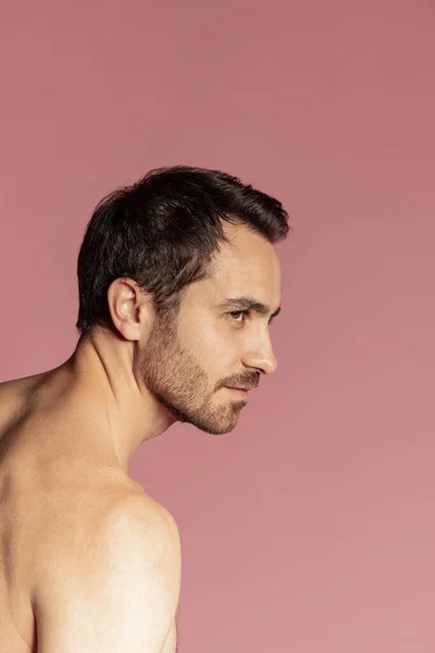 Lähikuva muotokuva nuori komea parrakas paidaton mies eristetty vaaleanpunainen studio tausta. Luonnonkauneus — kuvapankkivalokuva