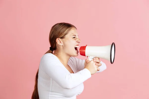 Porträtt av ung rödhårig flicka skriker på megafon isolerad över rosa studio bakgrund. Profilbild — Stockfoto