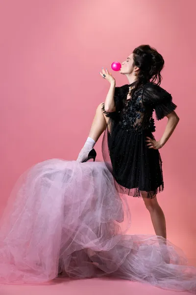 Retrato de jovem mulher bonita em preto vestido pequeno noite isolado no fundo rosa. Conceito de férias, moda, estilo — Fotografia de Stock
