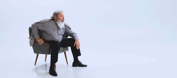 Retrato de homem barbudo sênior em estilo retro, moda dos anos 70, 80 anos sentado em cadeira isolada em fundo estúdio cinza — Fotografia de Stock