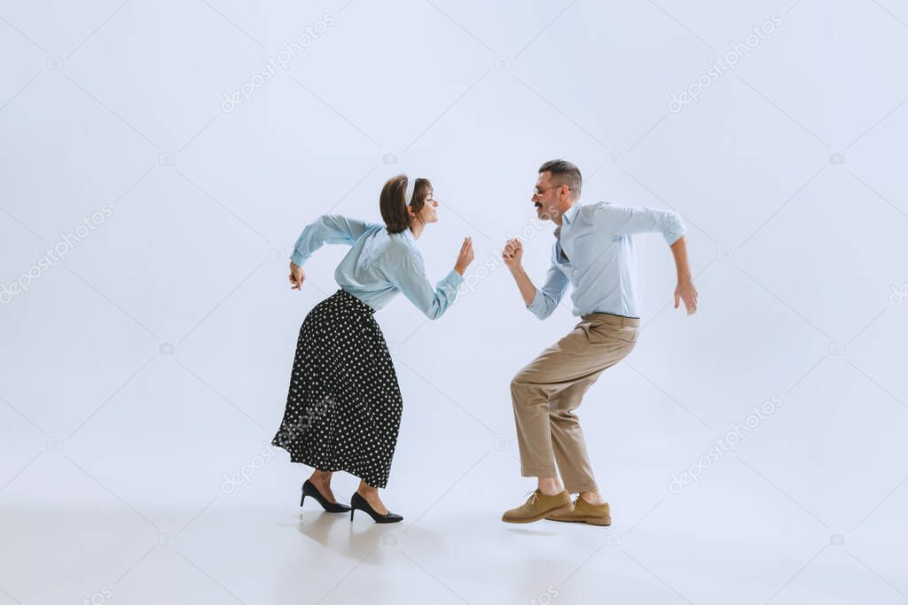 Two dancers, young man and woman in old-school fashioned attire dancing rock-and-roll isolated on white background