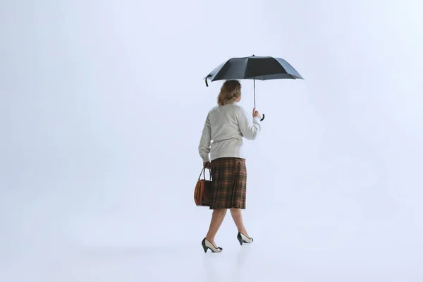 Ritratto di donna anziana triste in stile retrò, moda anni '70, anni' 60 camminando con ombrello isolato su sfondo bianco — Foto Stock