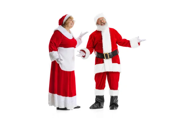 Emocionado homem sênior e bela mulher, Papai Noel e missis Claus em traje de Ano Novo tradicional isolado no fundo branco. — Fotografia de Stock