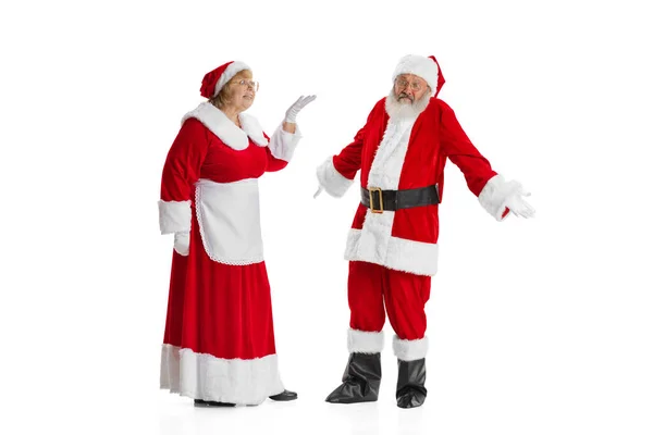 Két ember, idősebb férfi és nő, Mikulás és asszony Claus hagyományos újévi jelmezben beszél elszigetelt fehér háttér. — Stock Fotó