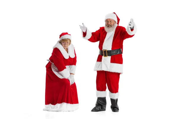 Excited senior man and beautiful woman, Santa Claus and missis Claus in traditional New Year costume isolated on white background. — Stock Photo, Image