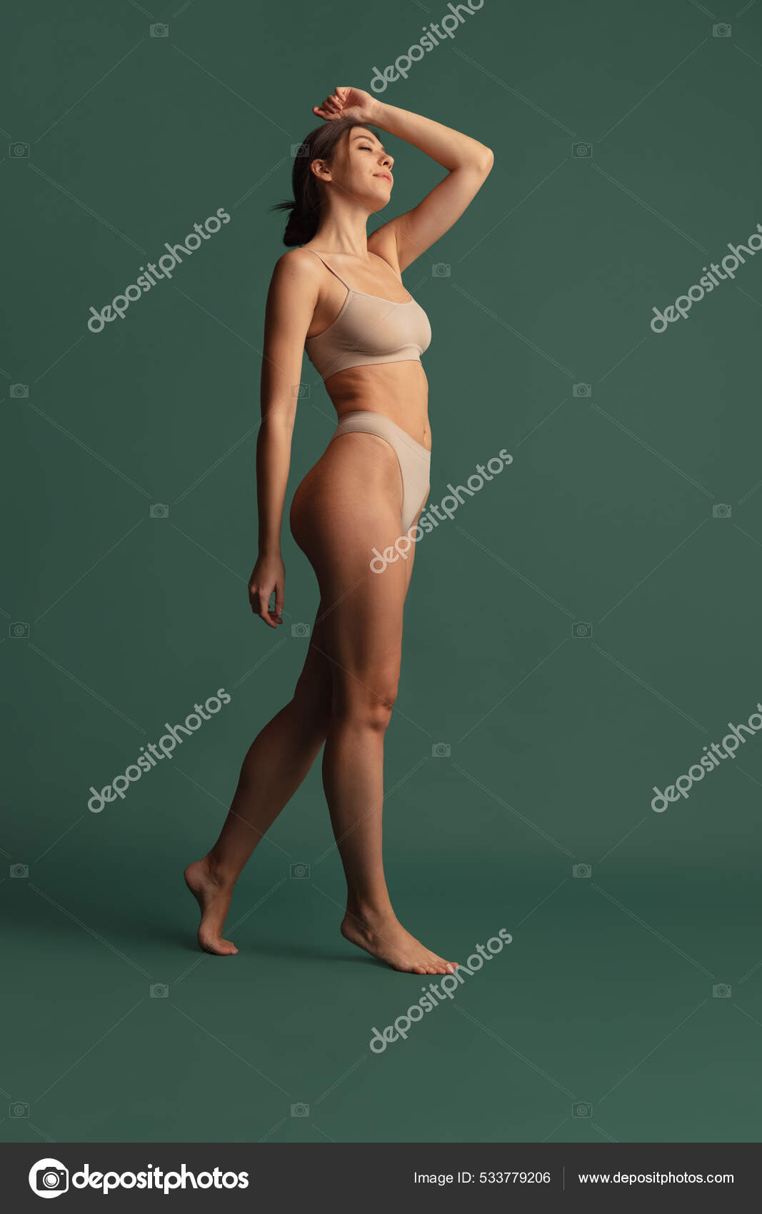 Portrait of young beautiful slim woman in nude color underwear posing  isolated over dark green studio background. Natural beauty concept. Stock  Photo by ©vova130555@gmail.com 533779206