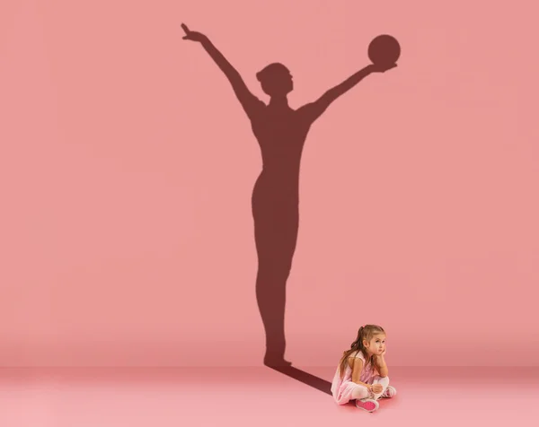 Εννοιολογική εικόνα με παιδί, κοριτσάκι και σκιά του γυναικείου γυμναστή στο στούντιο ροζ τοίχο. Όνειρα για αθλητική καριέρα — Φωτογραφία Αρχείου