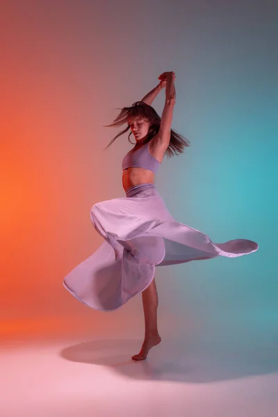 霓虹灯下渐变蓝色背景下的年轻而灵活的当代舞蹈演员的动态画像. — 图库照片
