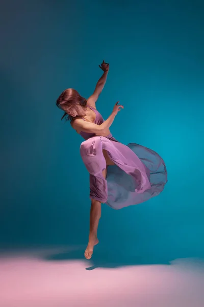 Una joven bailarina flexible de contemp en vestido lila bailando aislada sobre fondo azul degradado blanco en neón. —  Fotos de Stock