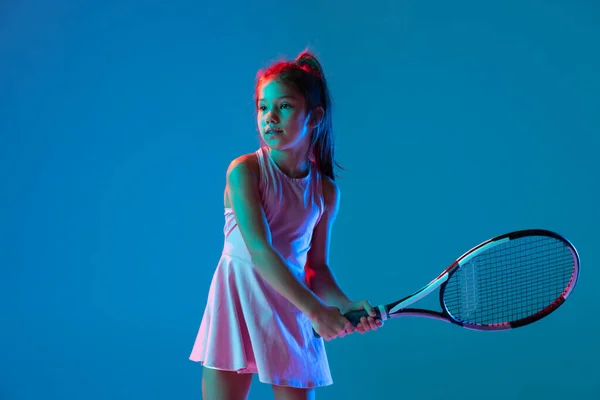 工作室拍摄的小女孩，初学者网球选手训练孤立在蓝光下的工作室背景。体育、学习、童年概念 — 图库照片
