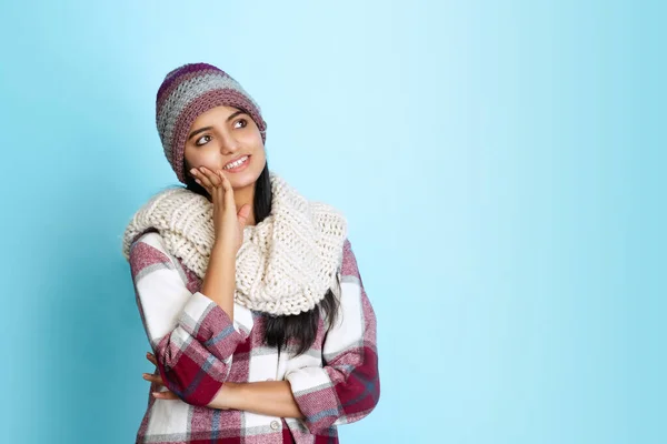 Portrait of young smiling girl, student in knitted hat and warm checkered shirt isolated on light blue studio backgroud — Stock Photo, Image