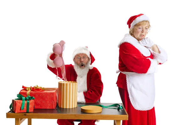 Aufgeregter Senior und schöne Frau mittleren Alters, Weihnachtsmann und Weihnachtsmann in traditioneller Neujahrstracht isoliert auf weißem Hintergrund. — Stockfoto