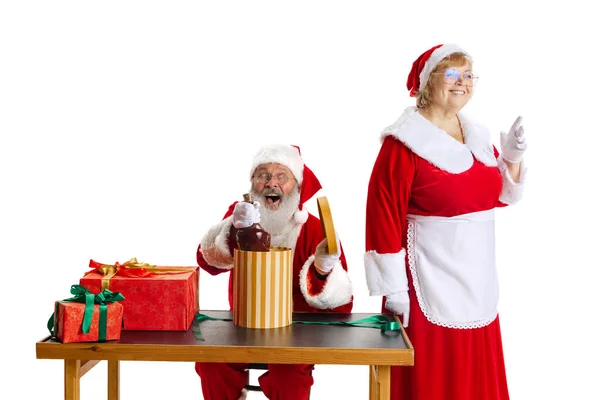 Älterer Mann und schöne Frau mittleren Alters, Weihnachtsmann und Weihnachtsmann in traditioneller Neujahrstracht isoliert auf weißem Hintergrund. — Stockfoto