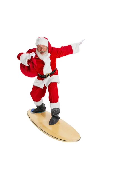 Portrait of emotional Santa Claus in red-white costume standing surfboard isolated on white background. Merry Christmas concept — Stock Photo, Image