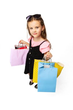Beyaz arka planda izole edilmiş çok renkli alışveriş paketleriyle duran şirin bir çocuğun stüdyo fotoğrafı..