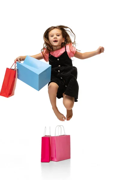 Retrato de belo menino bonito pulando com pacotes de compras isolados sobre fundo branco. — Fotografia de Stock