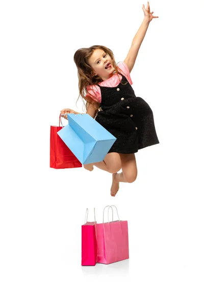 Портрет красивого маленького милого ребенка, прыгающего с пакетами покупок на белом фоне. — стоковое фото