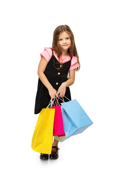스튜디오 촬영작고 귀여운 아이가 다양 한 색상의 쇼핑 패키지와서 백인 배경에 격리. — 스톡 사진
