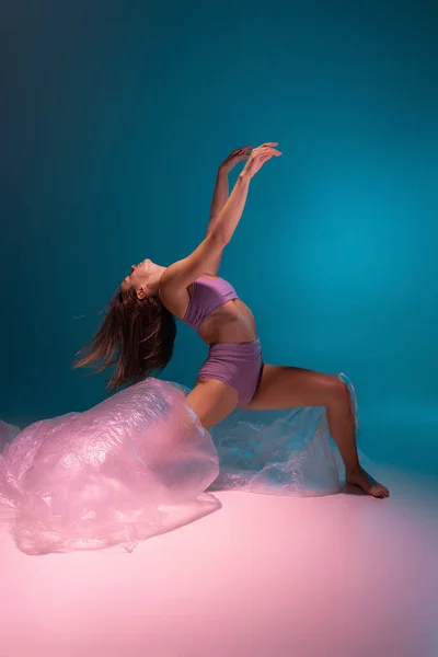 Un giovane ballerino flessibile che balla con tessuto isolato su sfondo bianco blu sfumato in luce al neon — Foto Stock