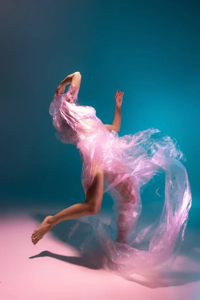 Сольное выступление. Красивая гибкая танцовщица танца с тканью, выделенной на градиентном синем фоне в неоновом свете — стоковое фото