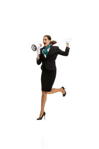 Portrait of beautiful young woman, flight attendant jumping with megaphone isolated on white studio background. — Stock Photo, Image