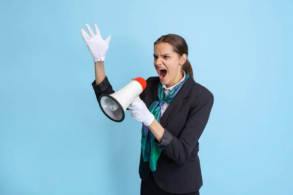 Portrét mladé ženy, letuška křičící na megafon izolované na modrém pozadí studia. — Stock fotografie