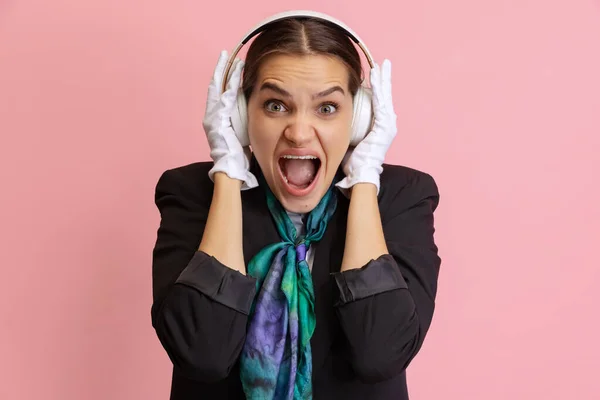 Närbild ganska ung skrikande kvinnlig flygvärdinna, flygvärdinna i hörlurar isolerad på rosa studio bakgrund. — Stockfoto