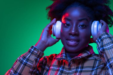 Yakın plan Afrikalı genç kızların portresi koyu yeşil arka planda, mor neon ışıkta. Afro saç modeli. İnsan duyguları kavramı