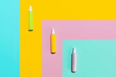 Üç renkli kavanoz, makyaj malzemeleri için sprey şişeleri, krem, losyon renkli arka planda izole edilmiş logolar olmadan..