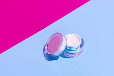 Parlak renkli arka planda markanız için açık cam krema kabı ve fotokopi alanı. Model