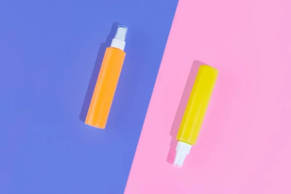 Två burkar, sprayflaskor för kosmetika, grädde, lotion utan logotyper isolerad över färgad bakgrund. Duoton — Stockfoto