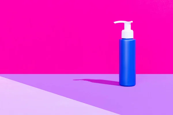 Uma garrafa de bomba azul para produtos cosméticos, creme, loção sem logotipos de pé isolado sobre fundo rosa magenta. — Fotografia de Stock