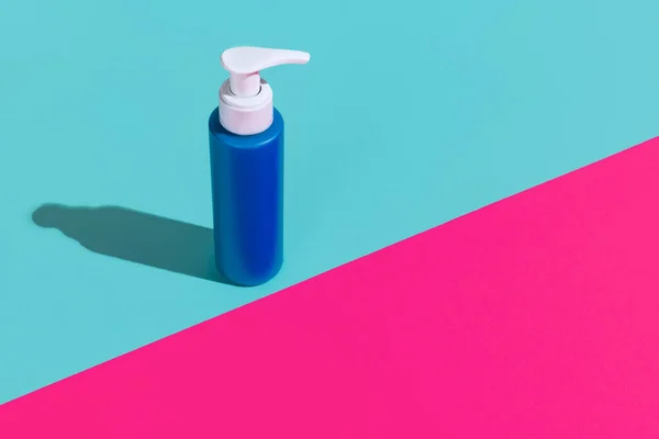 Uma garrafa de bomba azul para produtos cosméticos, creme, loção sem logotipos de pé isolado sobre fundo azul magenta. — Fotografia de Stock