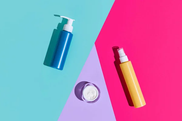Vista superior ot conjunto de diferentes frascos cosméticos, botellas y olla para crema sin logotipos aislados sobre fondo de color. — Foto de Stock