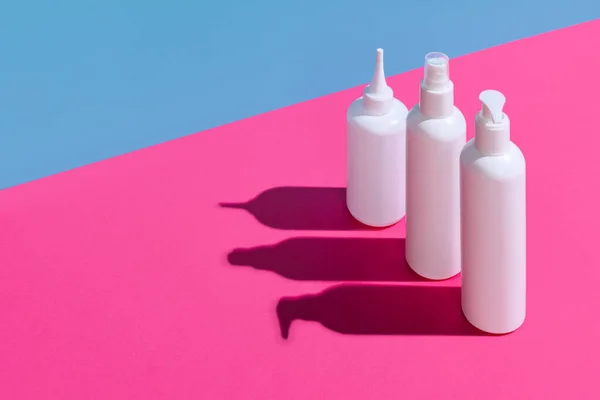 Cuidado de la piel, producto de belleza para el cuidado del cuerpo en macetas de plástico blanco para cosméticos sin logotipos aislados sobre fondo rosa y azul. —  Fotos de Stock