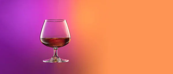 Flyer with cognac ballon, glass isolated over gradient purple and orange color background in neon. Concept of alcohol, holidays, New Year — Stock Photo, Image