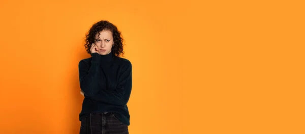 Retrato de jovem bela menina triste em suéter de malha quente é melancolia isolada no fundo de cor laranja — Fotografia de Stock