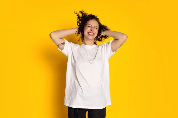 Portré mosolygós fiatal gyönyörű lány fehér pólóban és farmer nevetés elszigetelt sárga háttér — Stock Fotó