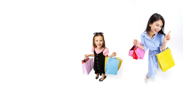 Vista de ángulo alto de la mujer joven y la niña con un montón de bolsas, paquetes brillantes de colores aislados sobre fondo de estudio blanco. Collage. — Foto de Stock