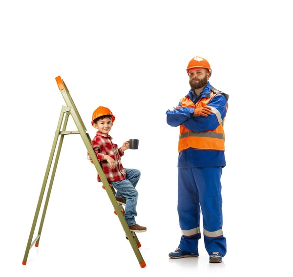 Ung skäggig man, byggmästare i uniform stående med liten unge, son isolerad på vit bakgrund. — Stockfoto