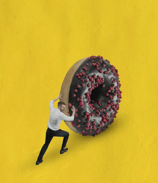 Collage de arte contemporáneo del hombre en tela clásica empujando gran donut chocolate cuesta arriba aislado sobre fondo amarillo — Foto de Stock