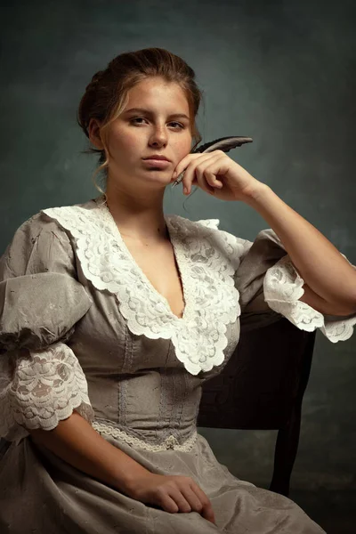 Κοντινό πλάνο πορτρέτο του νεαρού όμορφου κοριτσιού σε γκρι φόρεμα μεσαιωνικού στυλ απομονωμένο σε σκούρο φόντο. Σύγκριση της έννοιας των εποχών, στυλ ψύλλων. — Φωτογραφία Αρχείου