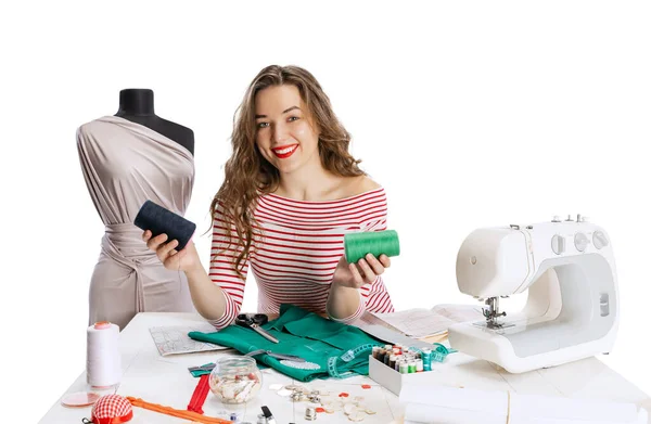 Cheerful beautiful young girl, seamstress, dressmaker working with fabric, scissors and sewing machine isolated on white background. Concept of job, hobby — Stock Photo, Image