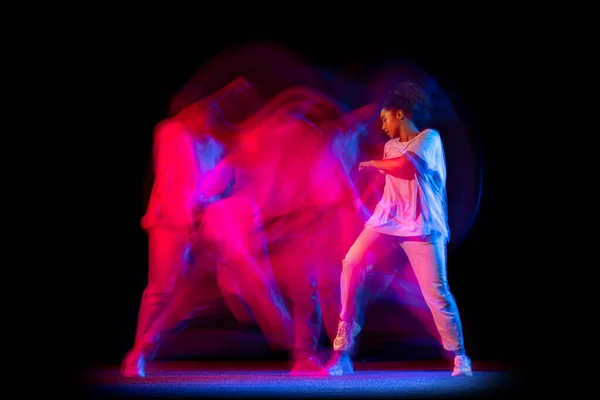 Menina esportiva em traje branco dança hip-hop dança isolada no fundo escuro no salão de dança em néon luz mista. — Fotografia de Stock