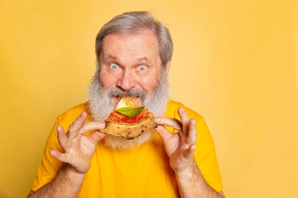 Κοντινό πλάνο ανώτερος αστείος άνθρωπος δαγκώνει ένα κομμάτι πίτσα απομονώνονται σε κίτρινο φόντο στούντιο. Παγκόσμια ημέρα πίτσας — Φωτογραφία Αρχείου