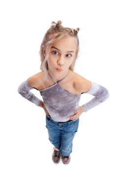 Güzel, küçük bir kızın yüksek açılı görüntüsü, günlük giysiler içinde çocuk eğleniyor, gri stüdyo arka planında izole edilmiş poz veriyor..