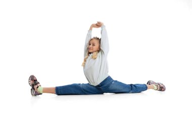 Şirin, komik küçük bir kız, günlük giysiler içinde beyaz stüdyo arka planında izole bir şekilde yerde oturan bir çocuk. Duygular