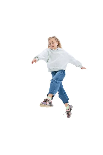 Динамічний портрет маленької дівчинки, дитина в повсякденному одязі стрибає, розважаючись ізольовано на сірому студійному фоні . — стокове фото