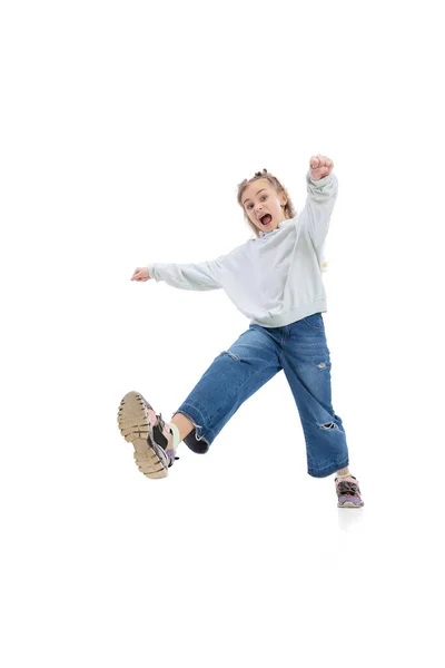 Portrait dynamique de petite fille, enfant en vêtements décontractés sautant, s'amusant isolé sur fond de studio gris. — Photo